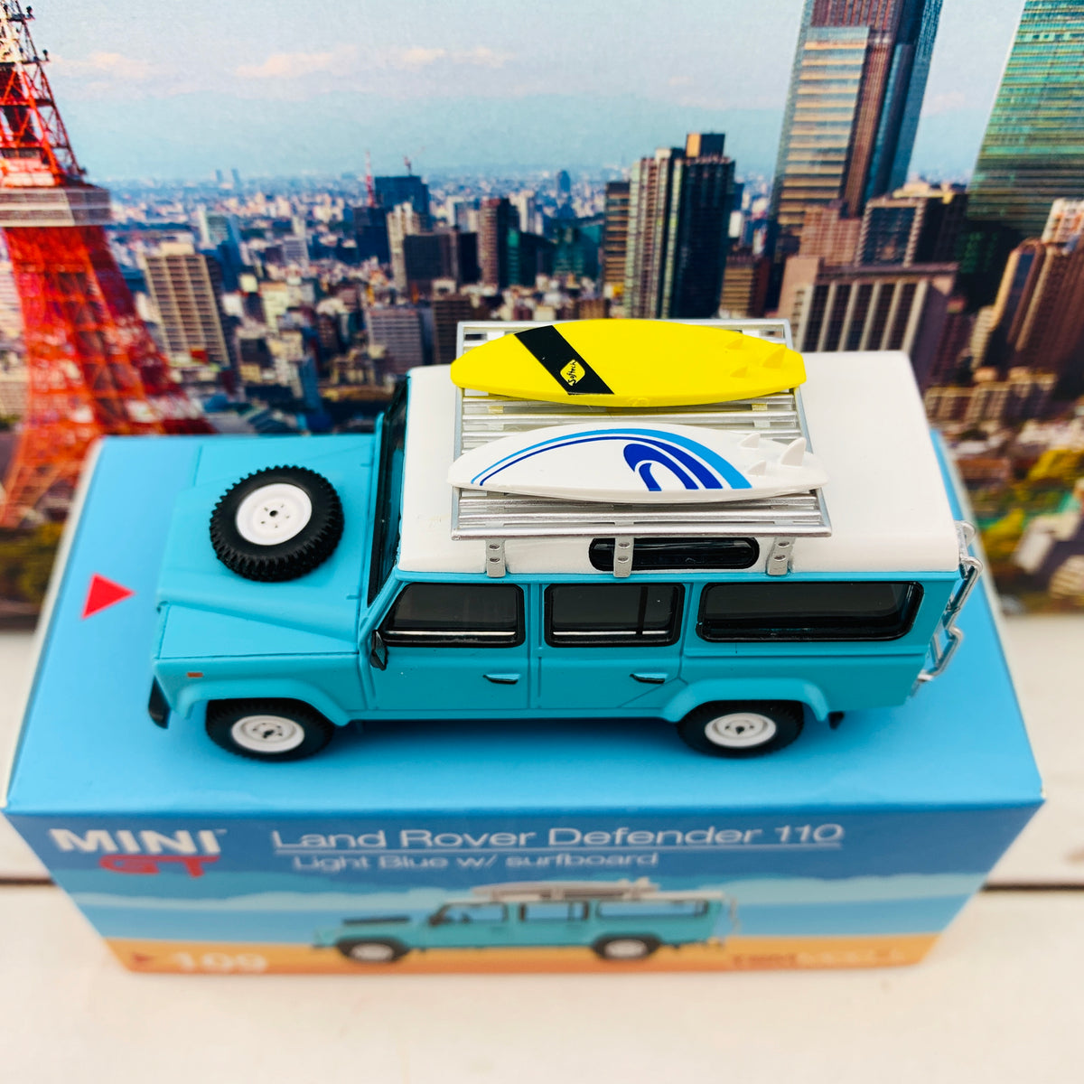 MINI GT 1/64 Land Rover Defender 110 Light Blue w/ Surfboard